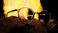 a pair of glasses sitting on a rock in front of a fire